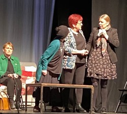 Group of actors on stage holding hands looking upset